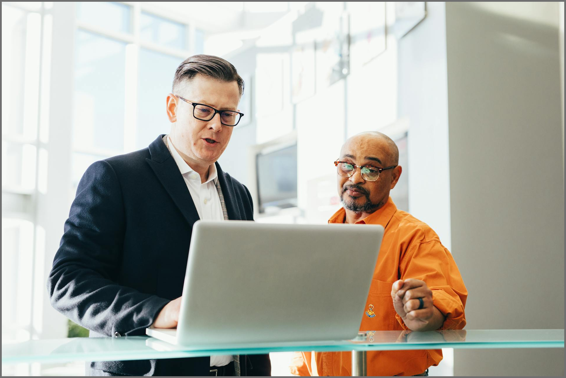 Team leader at laptop giving team member sales support.